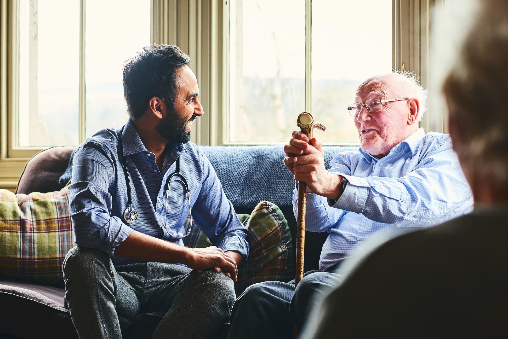An elderly man talking to a GP in his home.