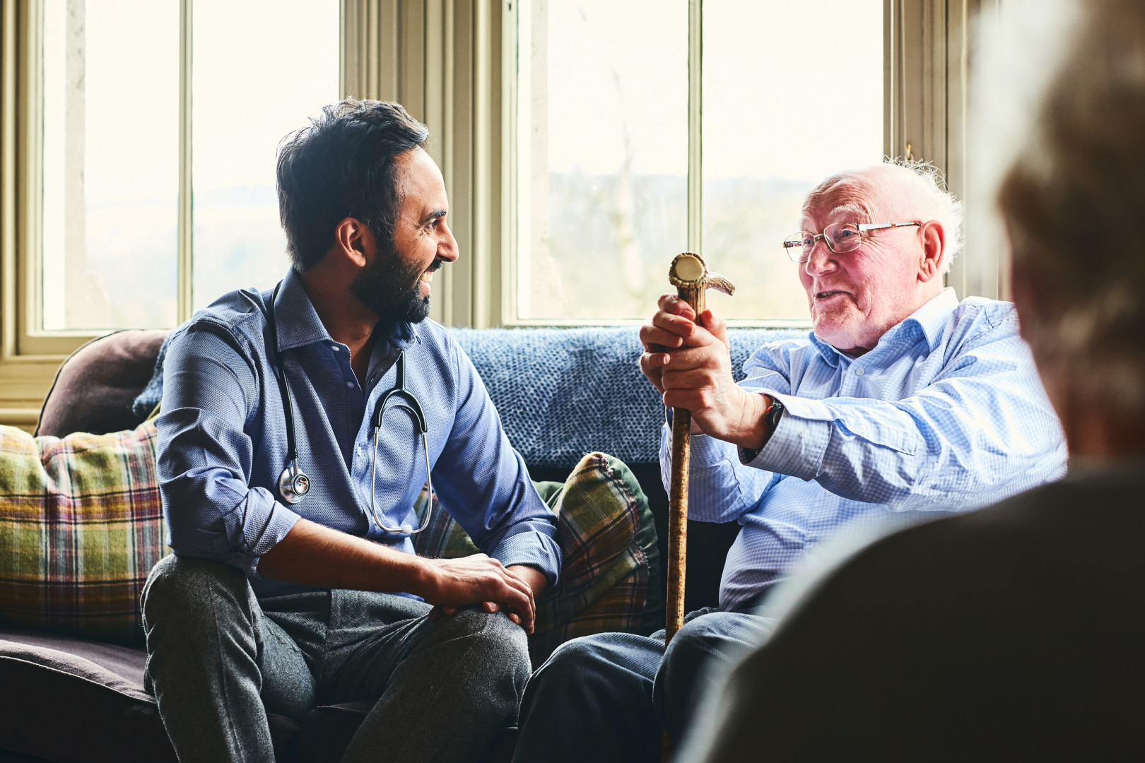 An elderly man talking to a GP in his home.